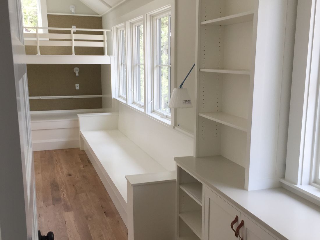 Built-in bunk room bench, bookshelves and desk in painted white cabinetry