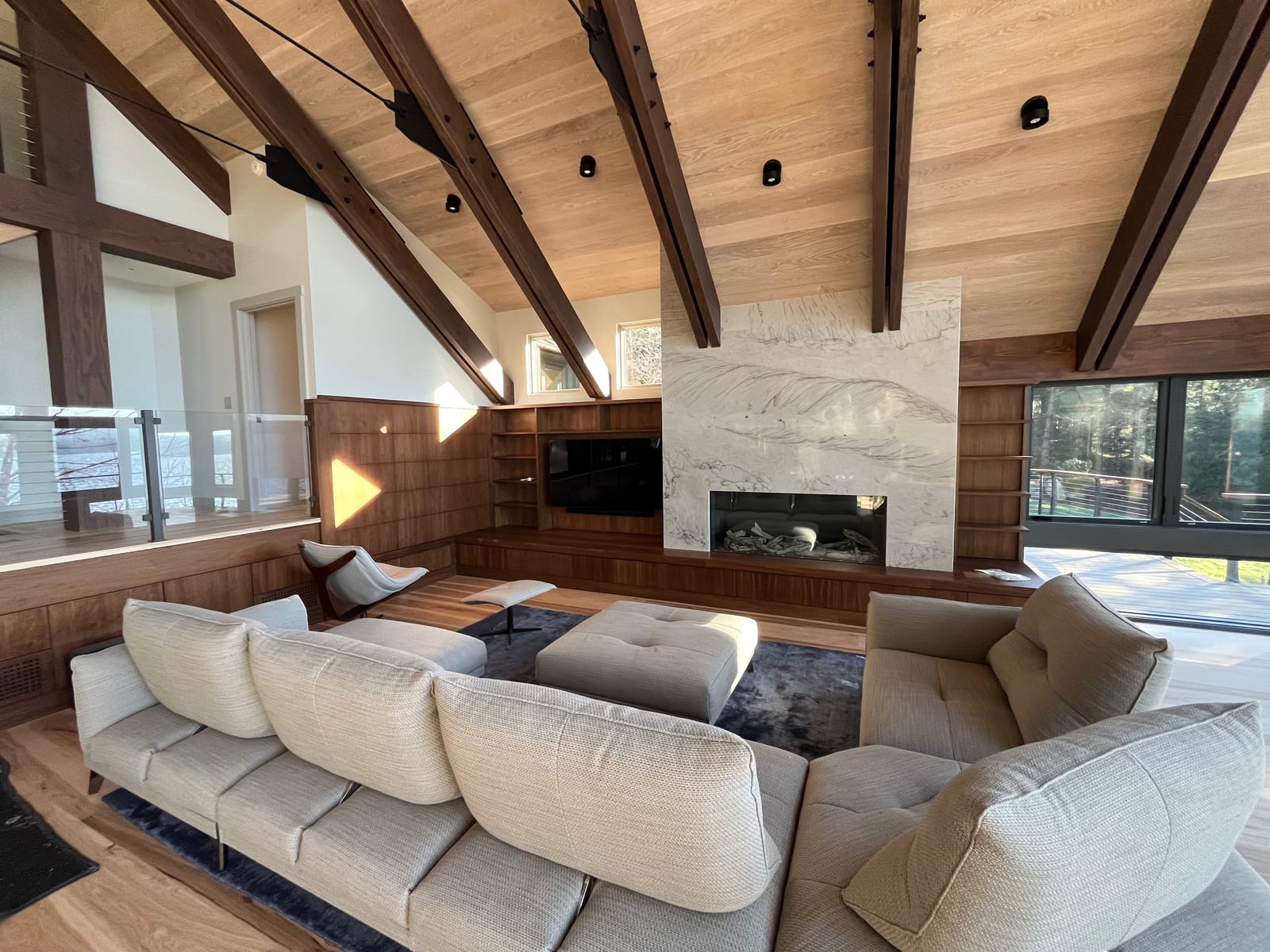 Living room with full-height walnut built-ins, floating shelves, an integrated media wall and a marble-clad fireplace surround under exposed beams