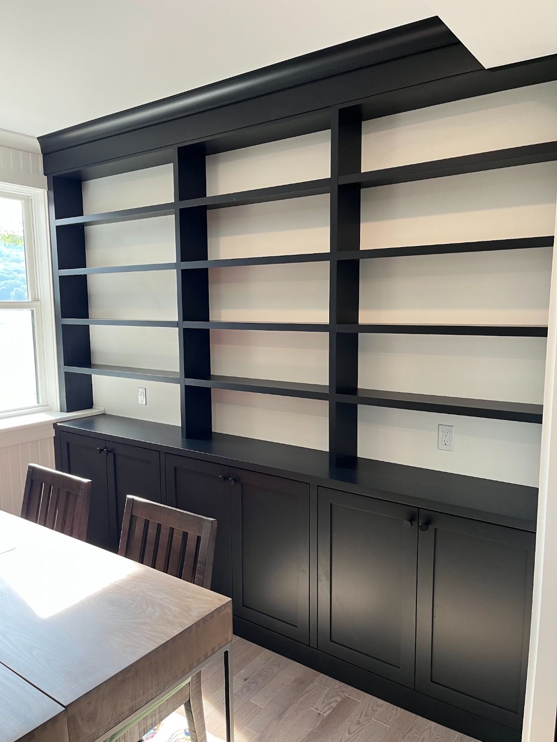 Dark navy built-in bookcase wall with open shelves over closed lower cabinets