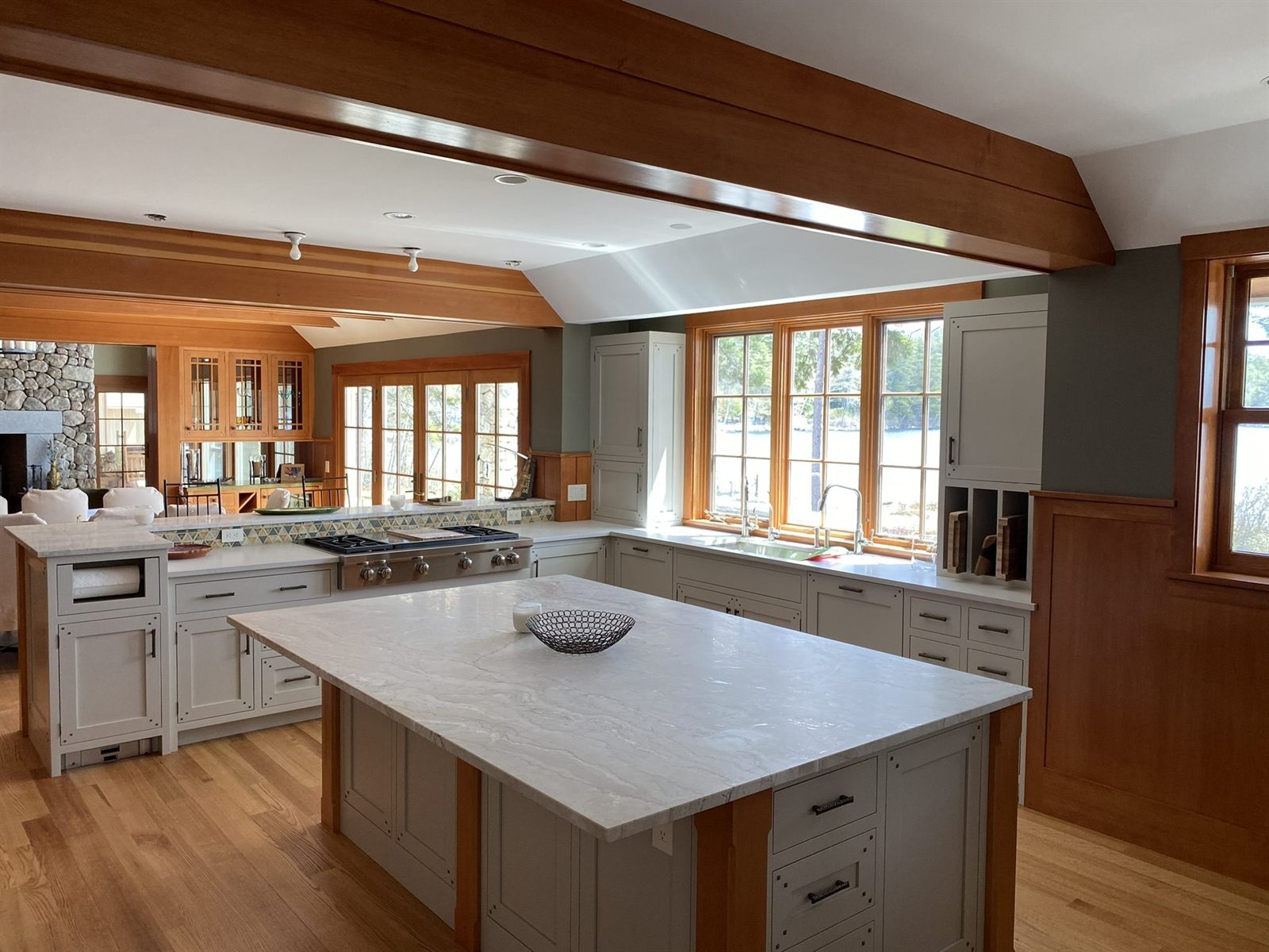 Lakeside craftsman kitchen with cherry ceiling beams, painted cabinetry and a marble island