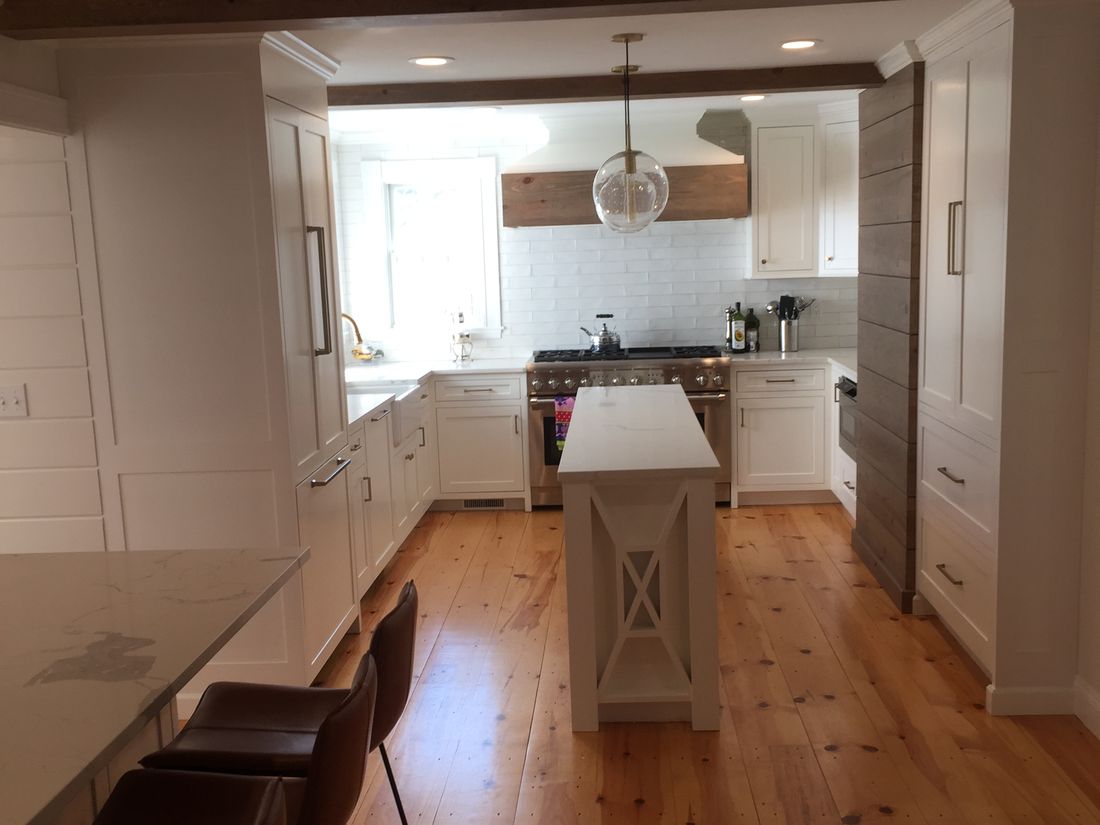 Farmhouse kitchen with white cabinetry, a reclaimed beam hood and wide pine floors