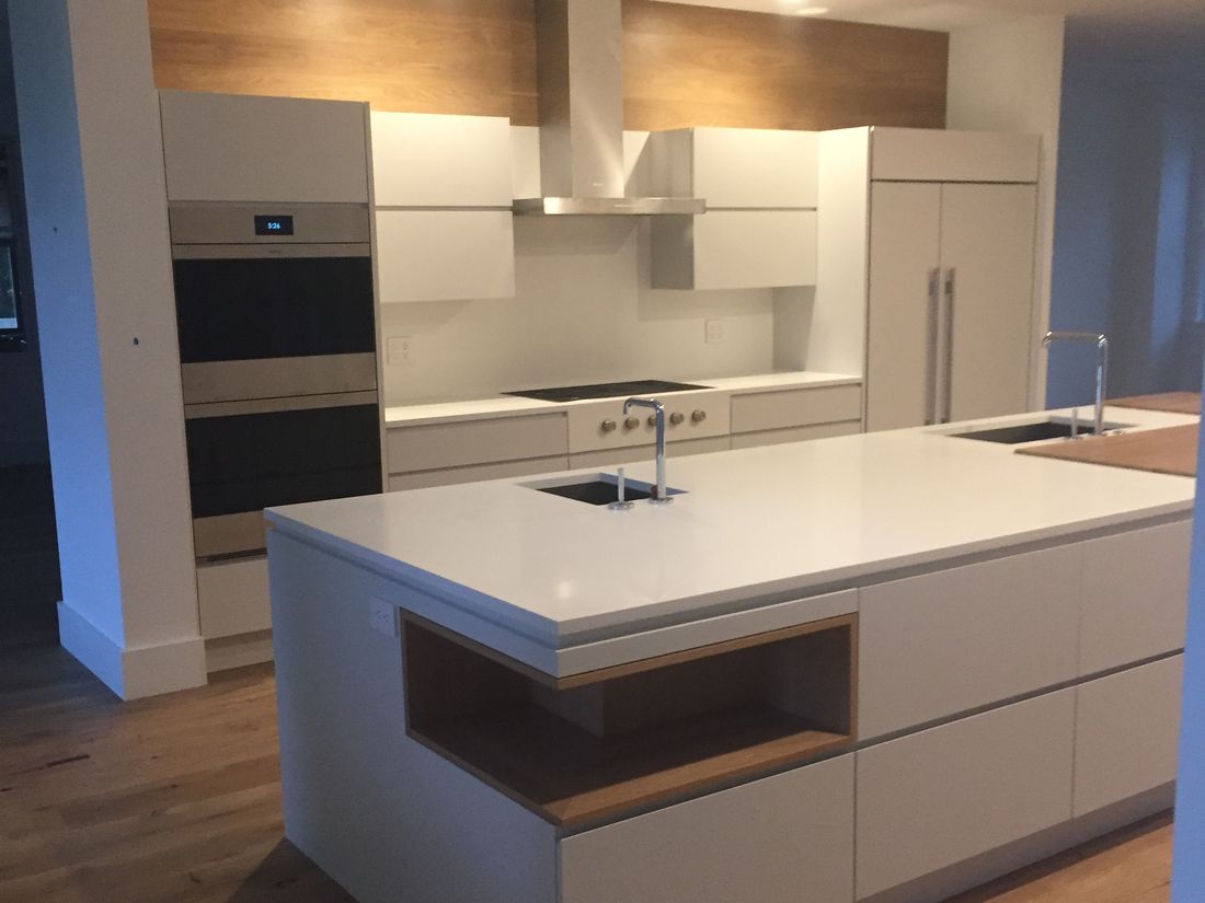 Modern kitchen island in white with an open oak-lined niche and integrated sink